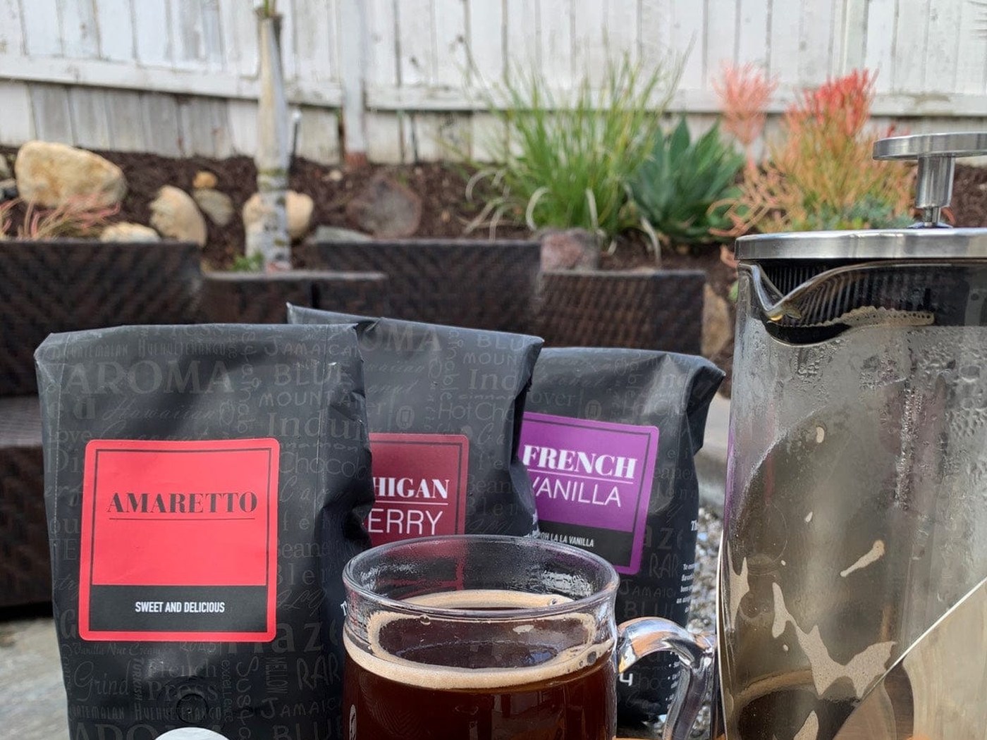 Coffee Beanery bags — Michigan Cherry, Café Carmel Cream and German Chocolate Cake — beside a travel tumbler