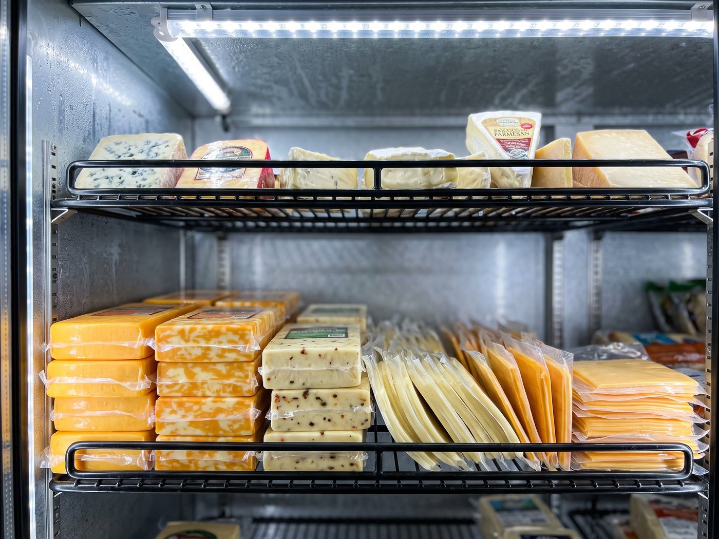 The refrigerated cheese shelf — blocks of cheddar and jack alongside packs of sliced cheese