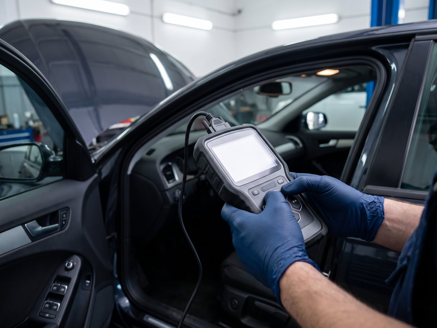 A technician running an OBD-II diagnostic scan from the driver’s seat of a customer car