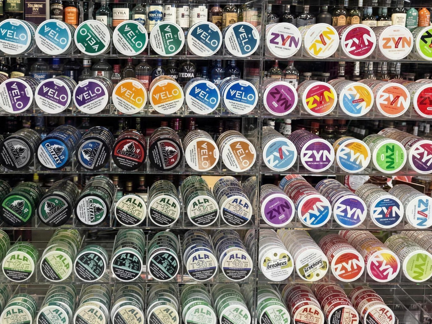 The pouch wall behind the counter — rows of ZYN, VELO, ALP, LUCY and FRE tins stacked by flavour