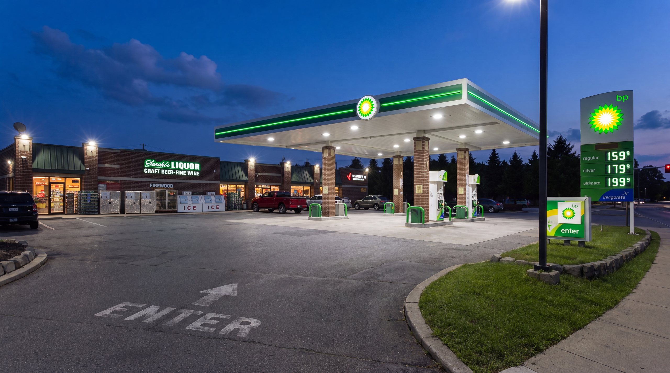 The Hometown Saroki's Cellar BP station in Wixom, Michigan at night — the lit BP canopy over the forecourt and the Saroki's Liquor storefront